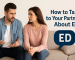 A supportive couple sitting on a couch, the man looking concerned while the woman listens and holds his hand, symbolizing open communication about erectile dysfunction.