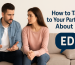 A supportive couple sitting on a couch, the man looking concerned while the woman listens and holds his hand, symbolizing open communication about erectile dysfunction.